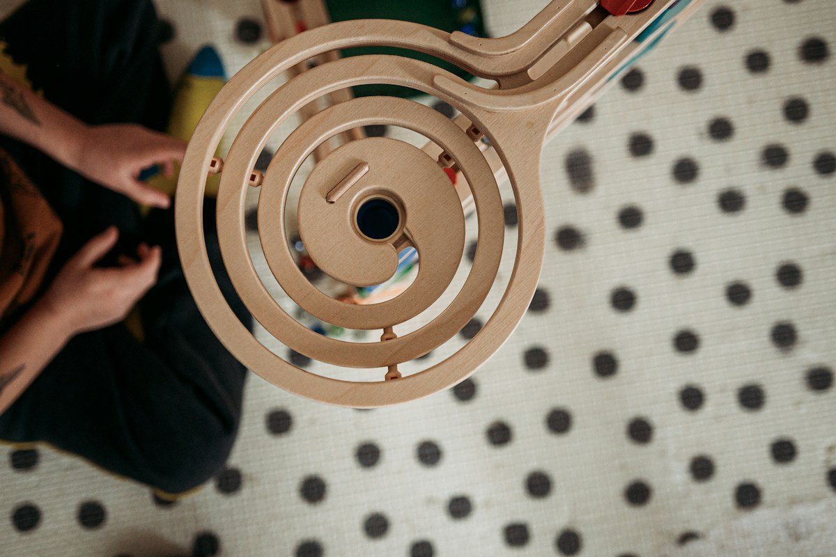 Murmelbahn aus Holz mit spiralförmiger Bahn auf einer gepunkteten Decke